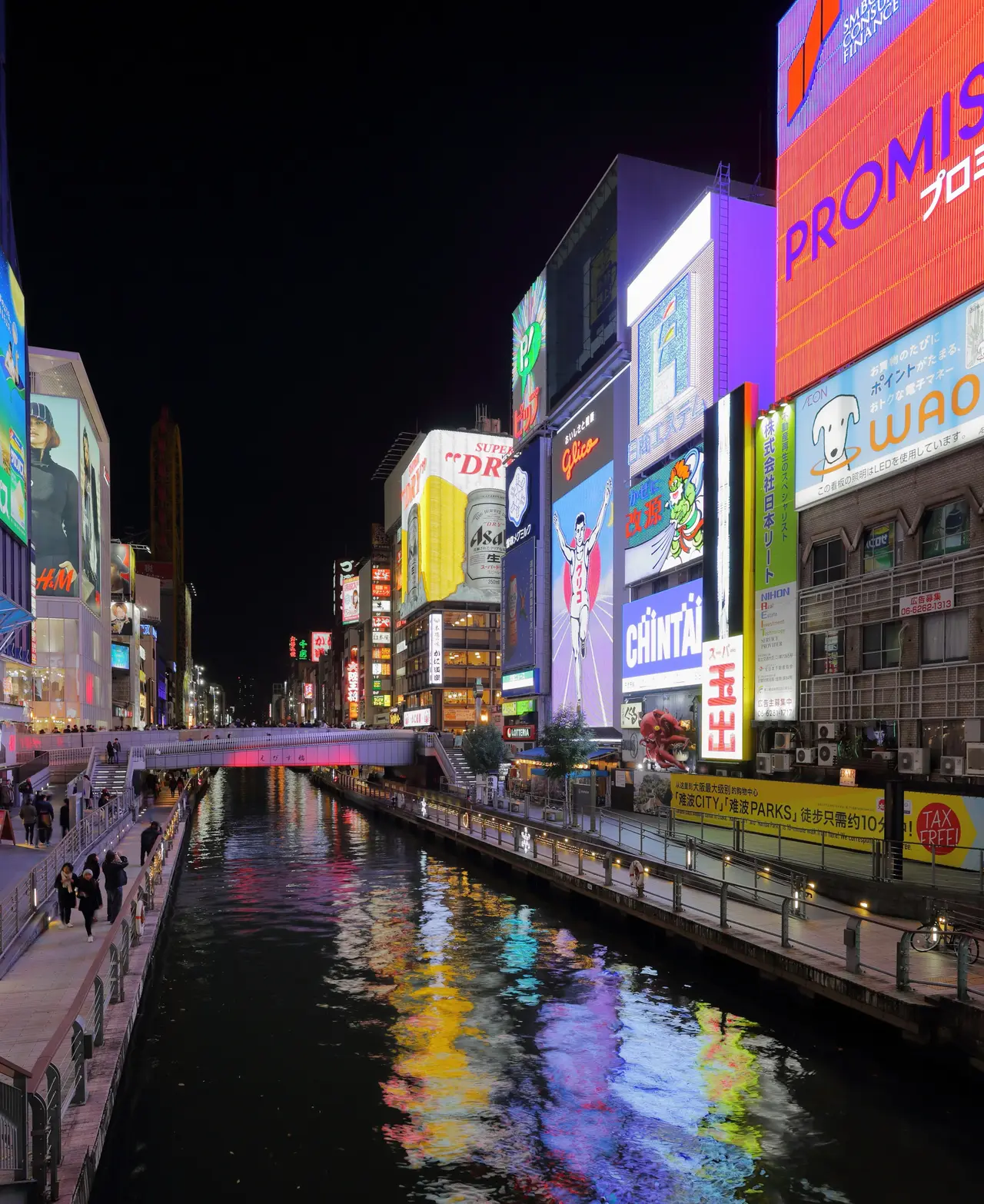 Canal de Dotonbori en Osaka de noche con anuncios de neón reflejados en el agua